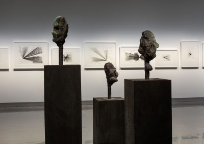 three sculptures of human heads sit in the middle of an empty gallery