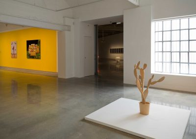 A yellow cactus sculpture in front of a window in a gallery