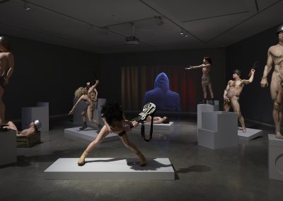 Various sculptures of naked soldiers on plinths in a gallery