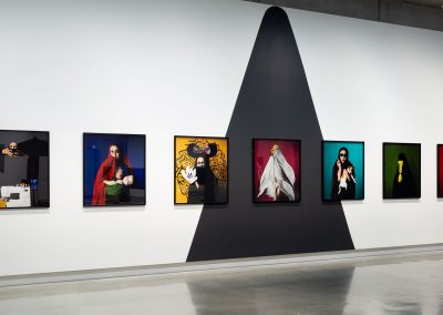 A series of paintings of a veiled woman in different characters on a gallery wall