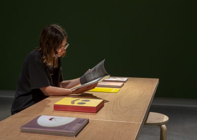 A woman looks at books at a table in a dark room