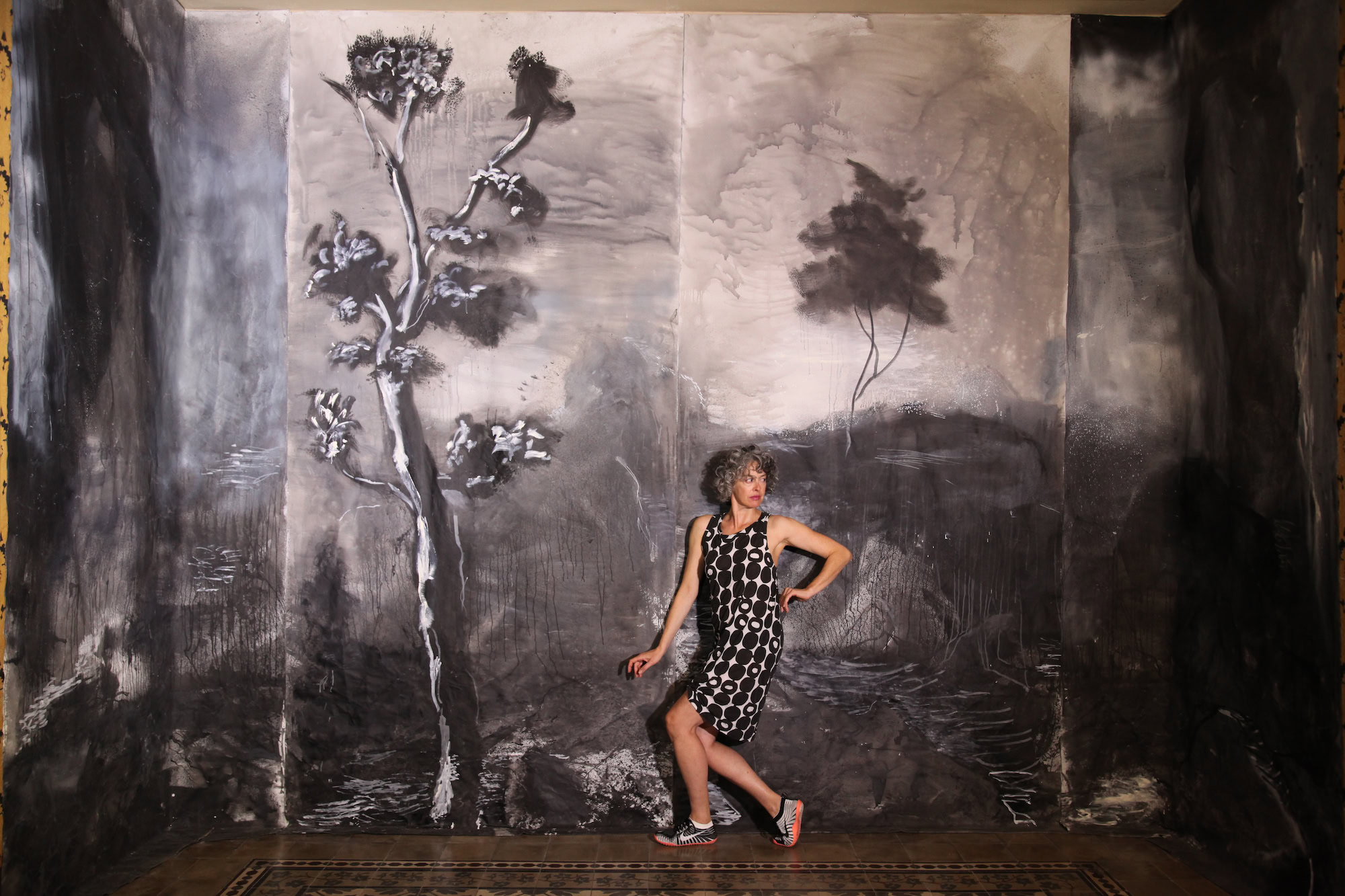 A dancer against the black-and-white landscape backdrop painted on the wall