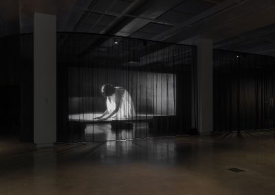 A thing black screen appears with a film still of a woman in a white dress kneeling over.