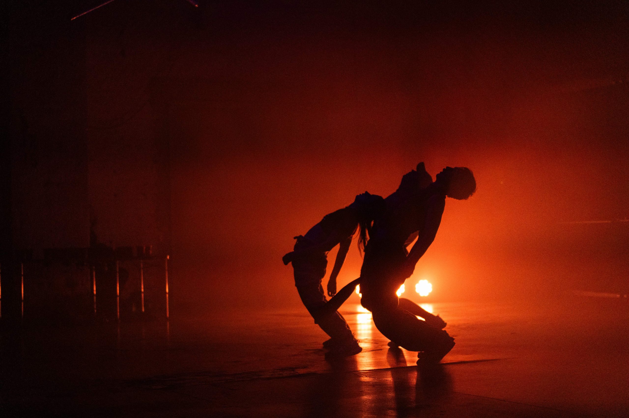 A silhouetted trio of dancers leaning backwards.