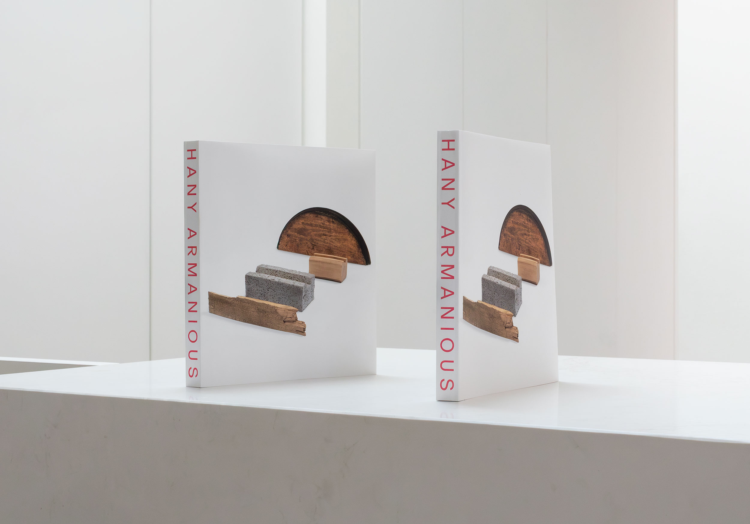 Two books with sculpture works sit on a white tabletop.