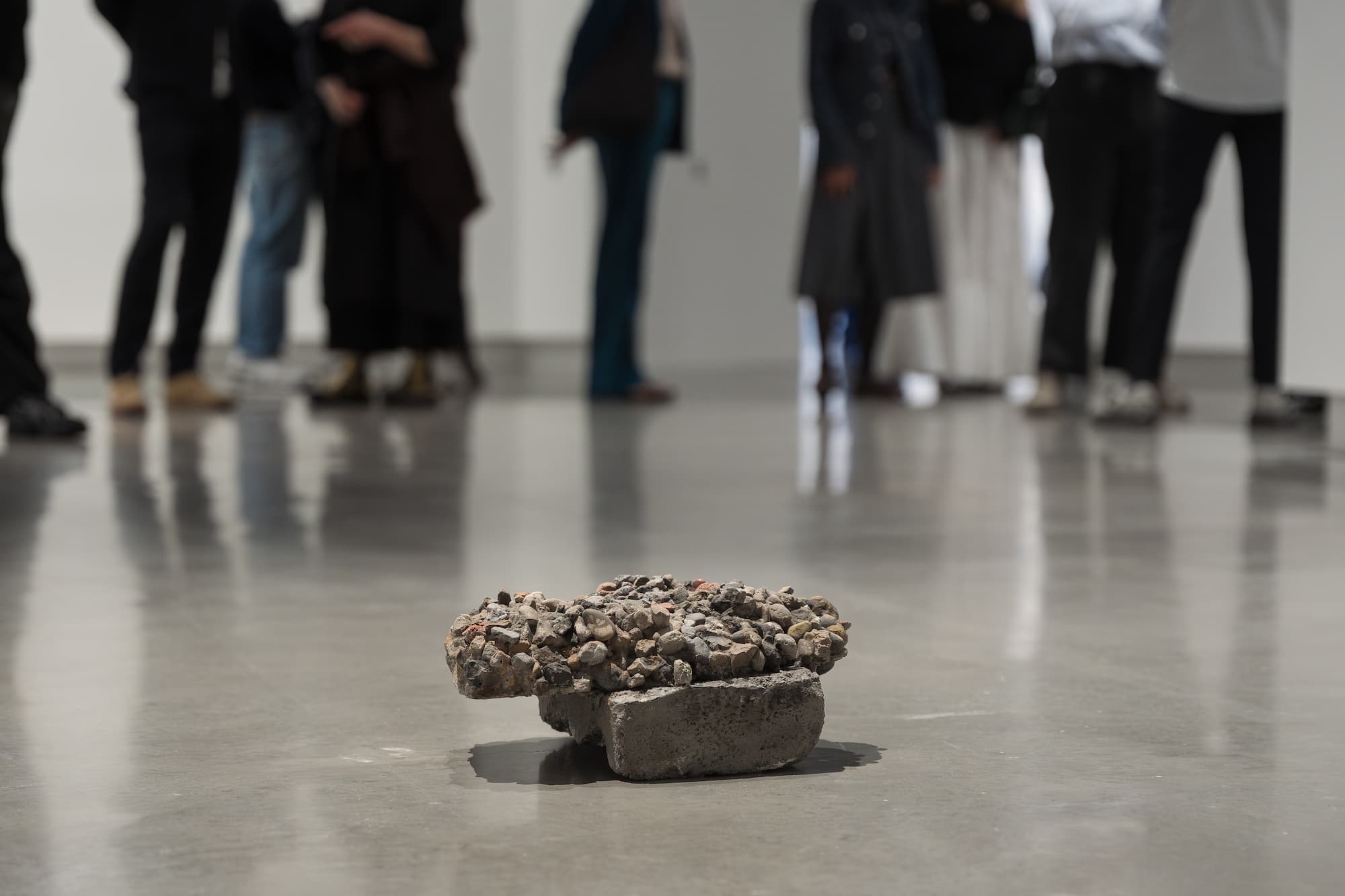 Photograph of "The World" artwork by Hany Armanious with a group of people in the background.