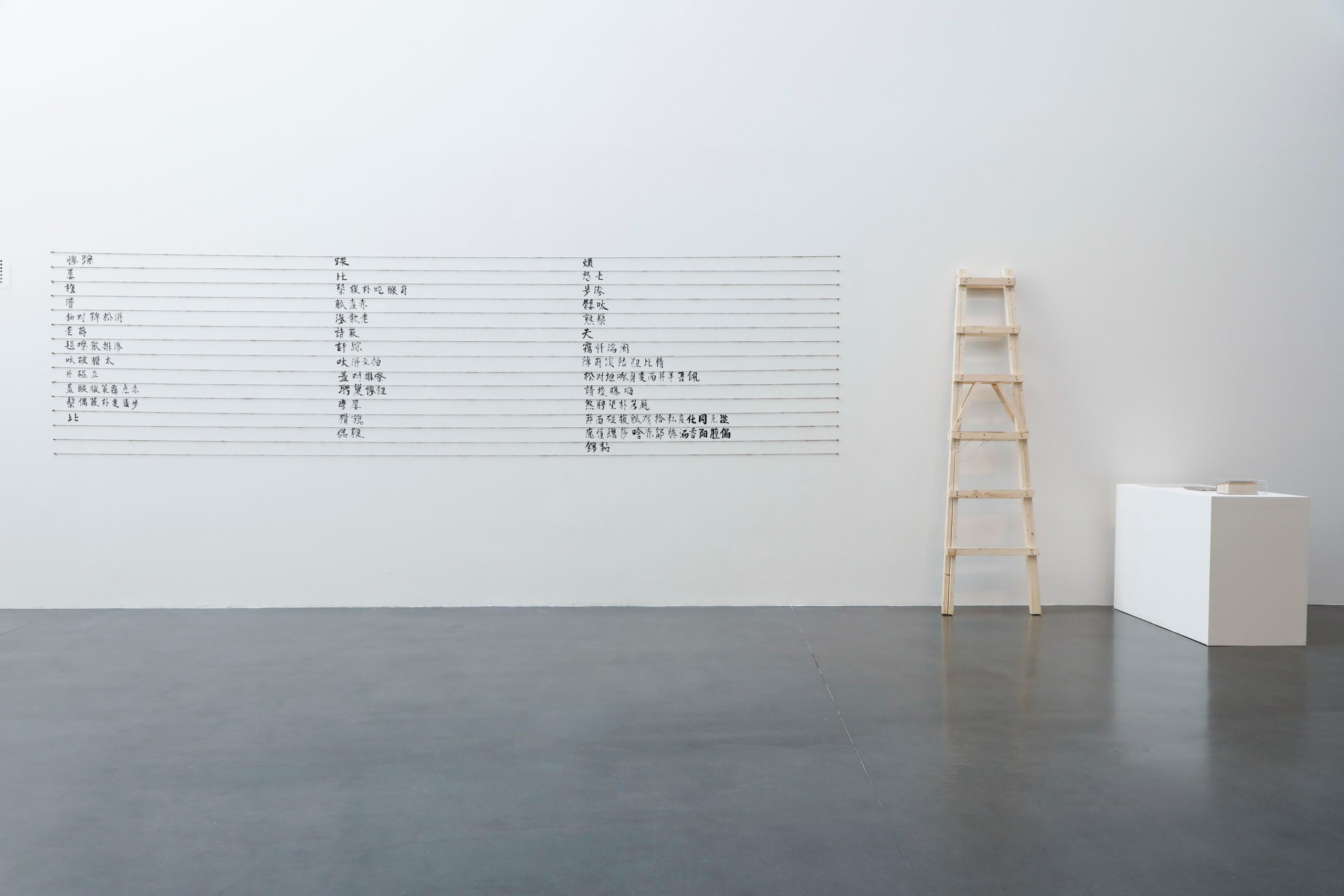Chinese writing in black ink on a white wall in three columns.