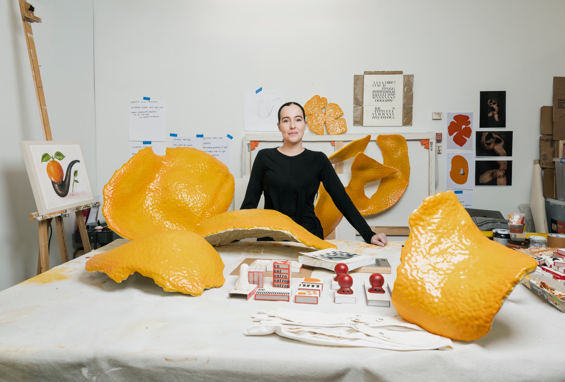 Darcey Bella Arnold stands in her studio surrounded by her works of large resign orange peels.